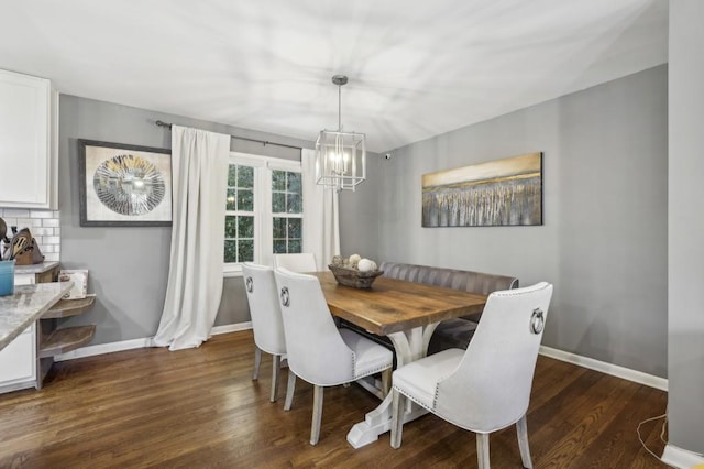 dining room with dark wood-style flooring, baseboards, and an inviting chandelier