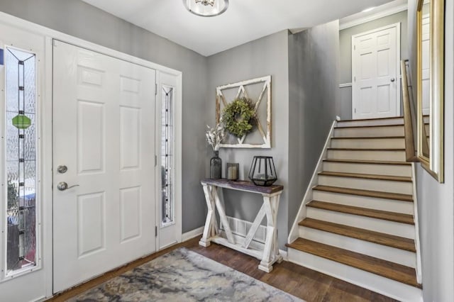 foyer entrance with stairs, baseboards, and dark wood-type flooring