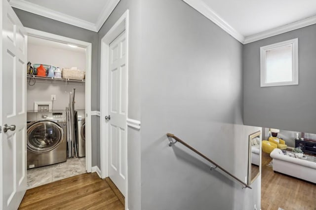 clothes washing area with laundry area, washing machine and dryer, ornamental molding, and wood finished floors