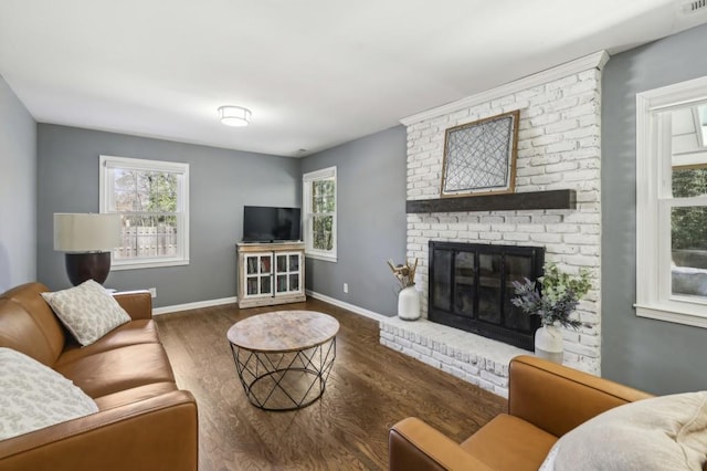 living area with a wealth of natural light, a fireplace, baseboards, and wood finished floors