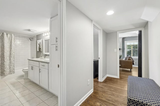 hallway with baseboards, a sink, and light wood-style floors