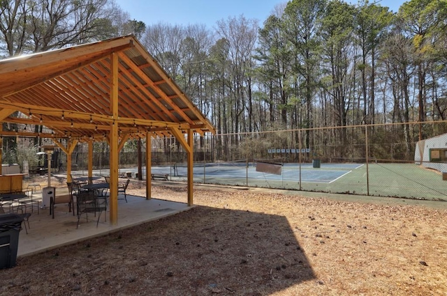 view of home's community with a tennis court and fence