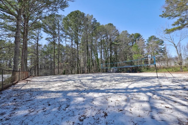 view of yard featuring volleyball court, a forest view, and fence