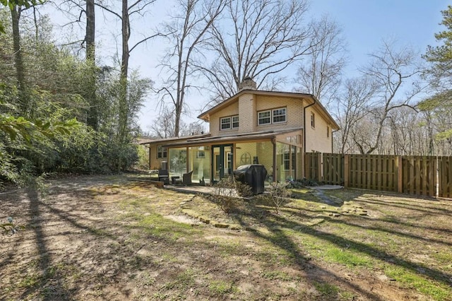 rear view of house with brick siding, fence, and a chimney