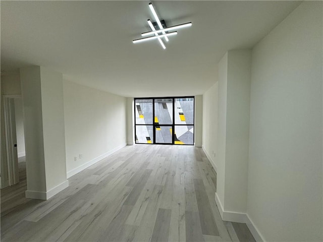 spare room with a wall of windows and light hardwood / wood-style flooring