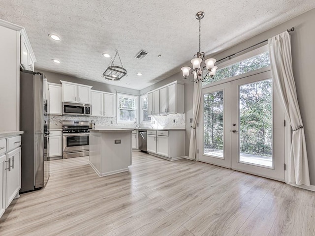 kitchen featuring tasteful backsplash, white cabinetry, a kitchen island, and stainless steel appliances