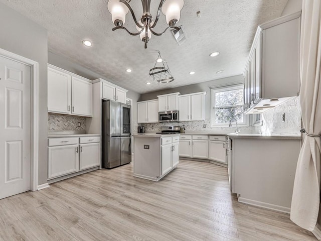 kitchen featuring a center island, white cabinets, hanging light fixtures, tasteful backsplash, and stainless steel appliances