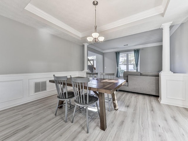 dining space with a notable chandelier, light hardwood / wood-style floors, ornamental molding, and a tray ceiling