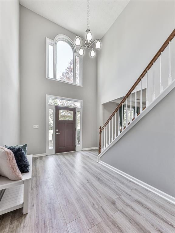 foyer entrance featuring a chandelier, a high ceiling, and light hardwood / wood-style flooring