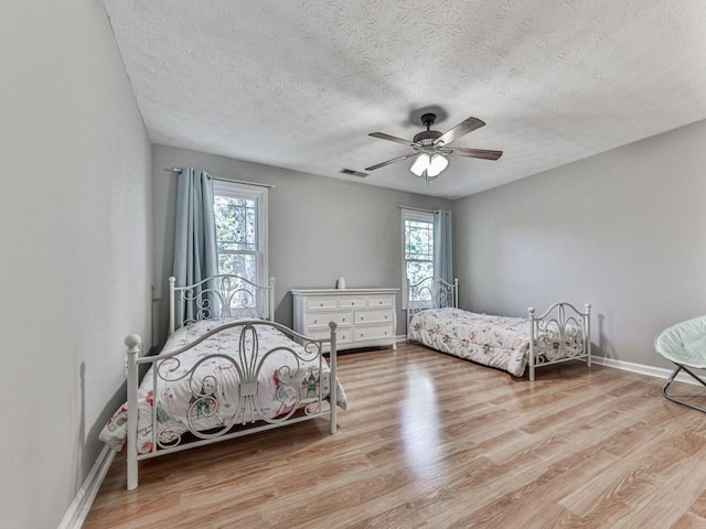 bedroom with ceiling fan, a textured ceiling, and light hardwood / wood-style flooring