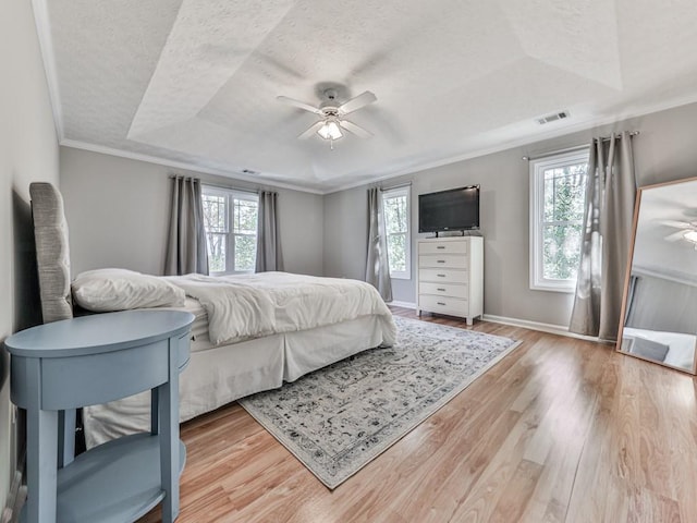 bedroom with multiple windows, a raised ceiling, ceiling fan, and ornamental molding