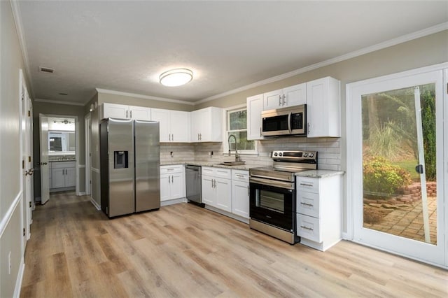 kitchen featuring stainless steel appliances, a sink, light stone countertops, backsplash, and white cabinets