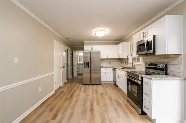kitchen featuring stainless steel appliances, a sink, white cabinetry, light wood finished floors, and backsplash