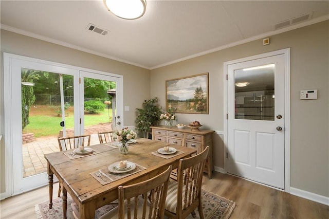 dining space featuring light wood finished floors and crown molding
