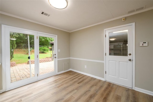 doorway to outside with wood finished floors, crown molding, and baseboards