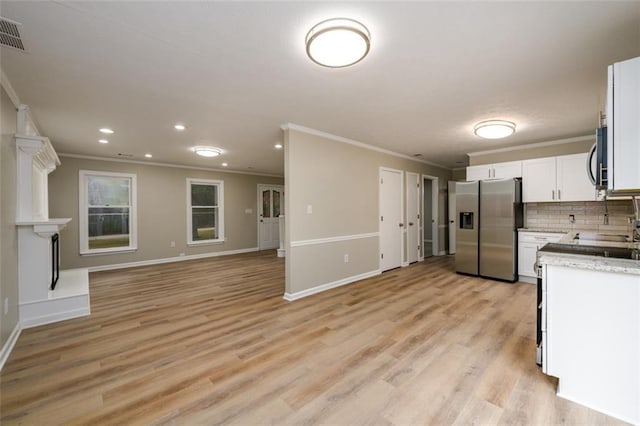 kitchen with stainless steel appliances, ornamental molding, open floor plan, white cabinetry, and light wood-style flooring