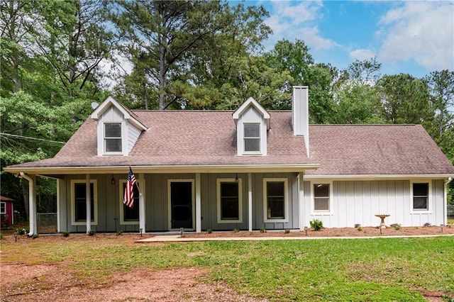 view of front of house with a chimney, board and batten siding, a front yard, and a porch