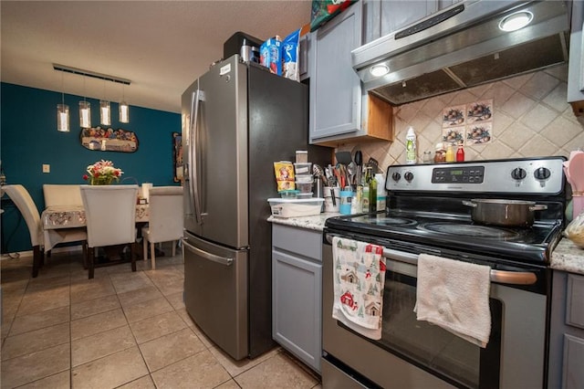 kitchen with light tile patterned floors, stainless steel appliances, decorative backsplash, gray cabinetry, and under cabinet range hood