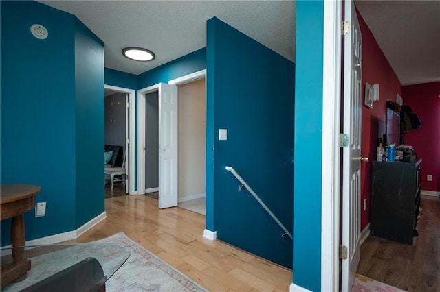 interior space featuring wood finished floors, an upstairs landing, and baseboards