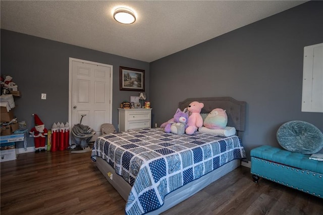 bedroom with a textured ceiling, electric panel, baseboards, and wood finished floors