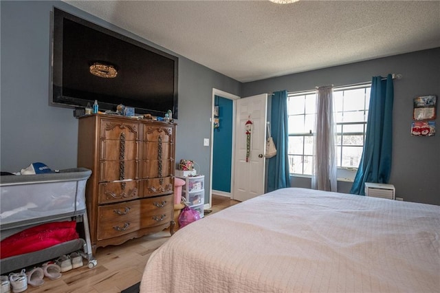 bedroom with a textured ceiling, baseboards, and wood finished floors