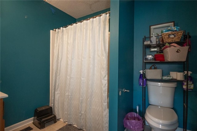 full bath featuring baseboards, toilet, a shower with curtain, tile patterned floors, and a textured ceiling