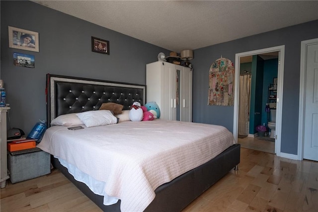 bedroom with light wood-style floors, a textured ceiling, and baseboards