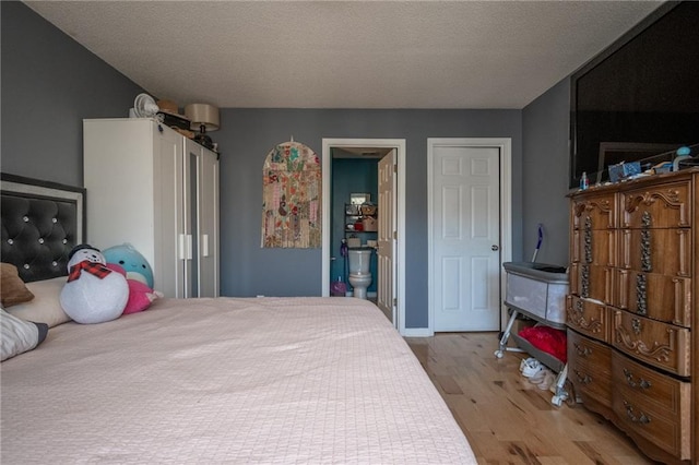 bedroom with a textured ceiling, wood finished floors, and ensuite bathroom