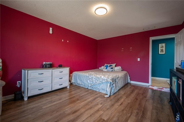 bedroom with visible vents, baseboards, and wood finished floors