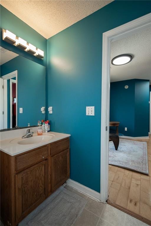 bathroom with baseboards, a textured ceiling, and vanity