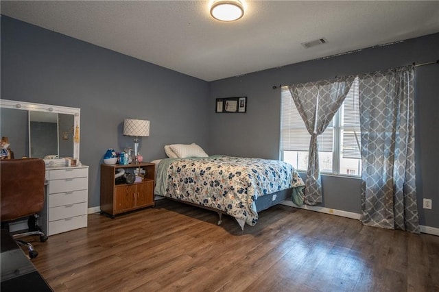 bedroom featuring visible vents, baseboards, and wood finished floors