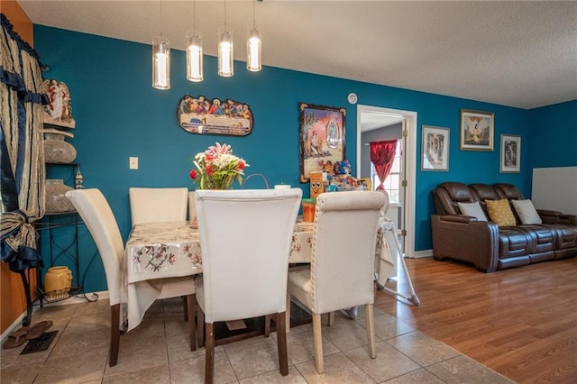 dining room with a textured ceiling, wood finished floors, and baseboards