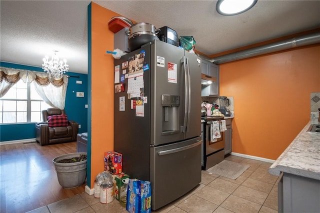 kitchen featuring light tile patterned floors, light countertops, appliances with stainless steel finishes, a textured ceiling, and a chandelier