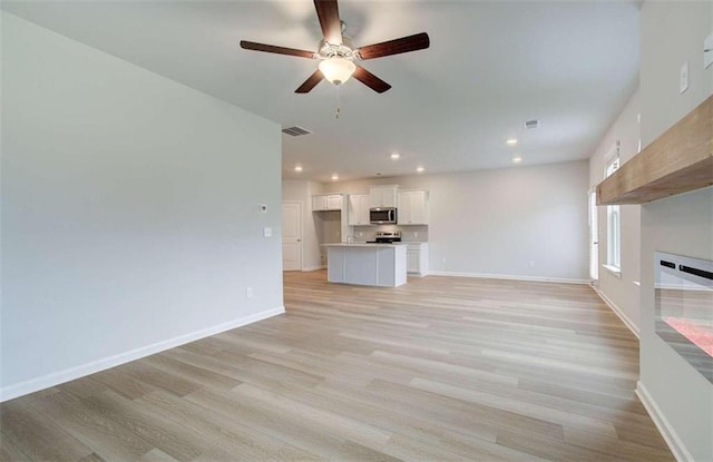 unfurnished living room featuring ceiling fan and light wood-type flooring