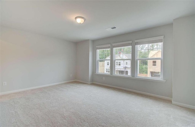 spare room featuring light colored carpet and a healthy amount of sunlight