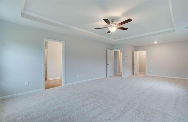 empty room featuring light carpet, ceiling fan, and a raised ceiling