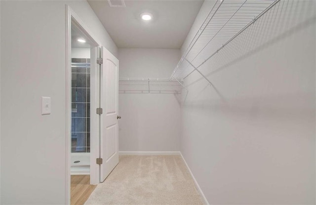 spacious closet featuring light colored carpet