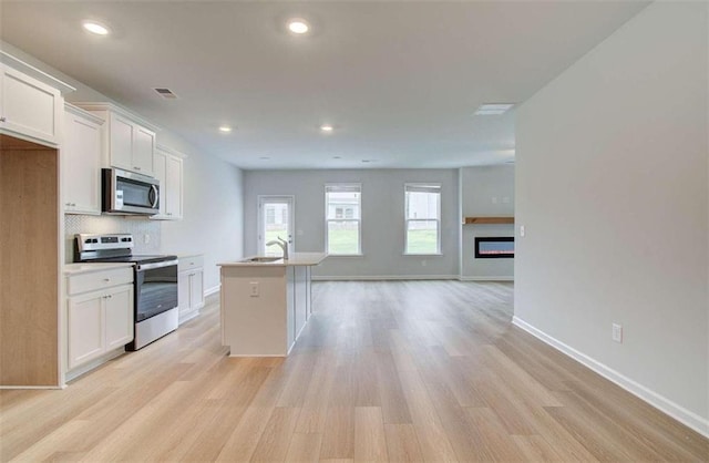 kitchen featuring sink, white cabinetry, appliances with stainless steel finishes, and a kitchen island with sink