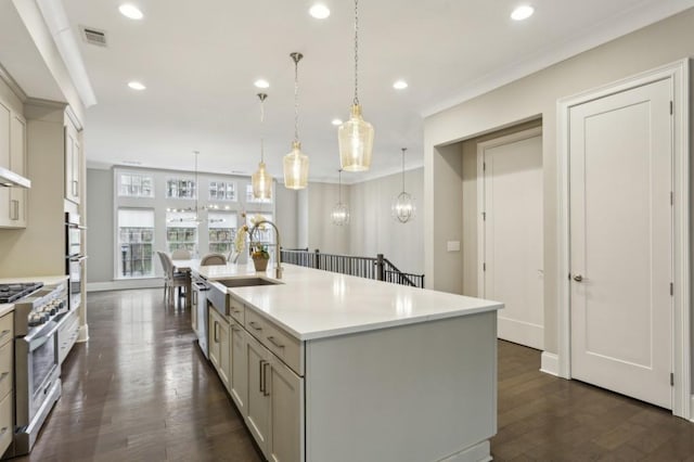 kitchen with light countertops, appliances with stainless steel finishes, a kitchen island with sink, recessed lighting, and dark wood-style flooring