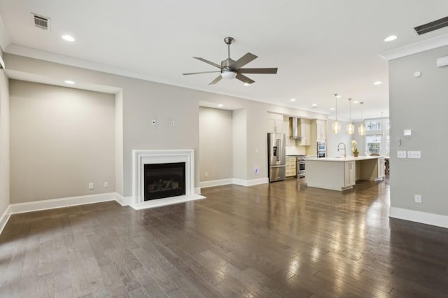 unfurnished living room featuring a ceiling fan, dark wood-type flooring, baseboards, and visible vents