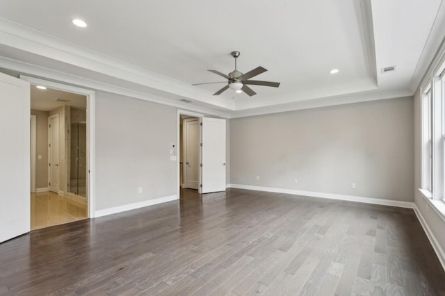 spare room with a tray ceiling, baseboards, wood finished floors, and a ceiling fan