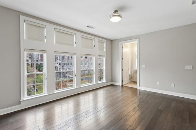 spare room featuring baseboards, dark wood-style floors, and visible vents