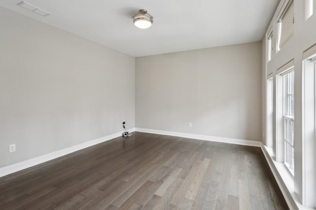 spare room with dark wood-style floors, baseboards, and visible vents