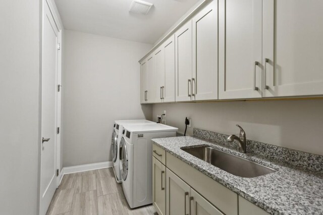 clothes washing area with a sink, baseboards, independent washer and dryer, visible vents, and cabinet space