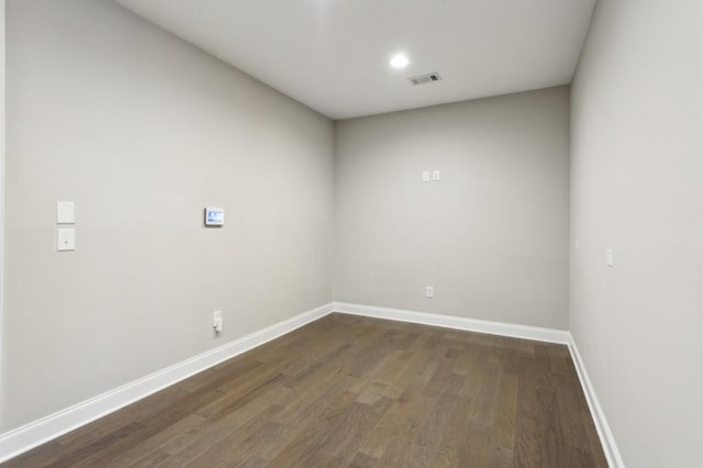 unfurnished room featuring baseboards, visible vents, and dark wood finished floors