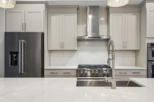 kitchen with decorative backsplash, wall chimney range hood, hanging light fixtures, gray cabinetry, and high quality appliances