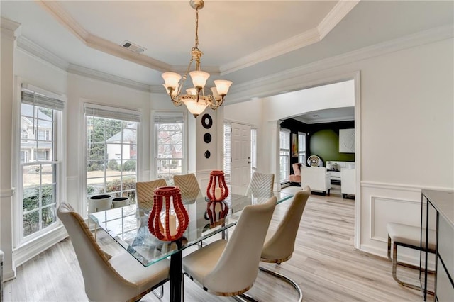 dining space with visible vents, an inviting chandelier, light wood-style flooring, arched walkways, and wainscoting