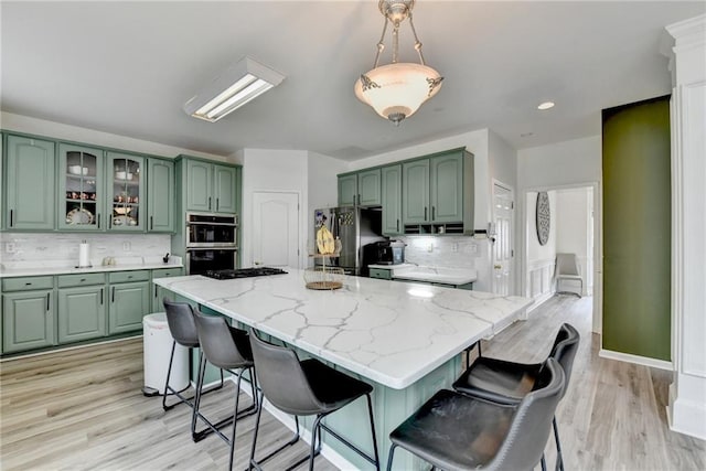 kitchen featuring backsplash, appliances with stainless steel finishes, a breakfast bar area, and green cabinets