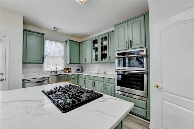 kitchen featuring green cabinets, stainless steel appliances, and a sink