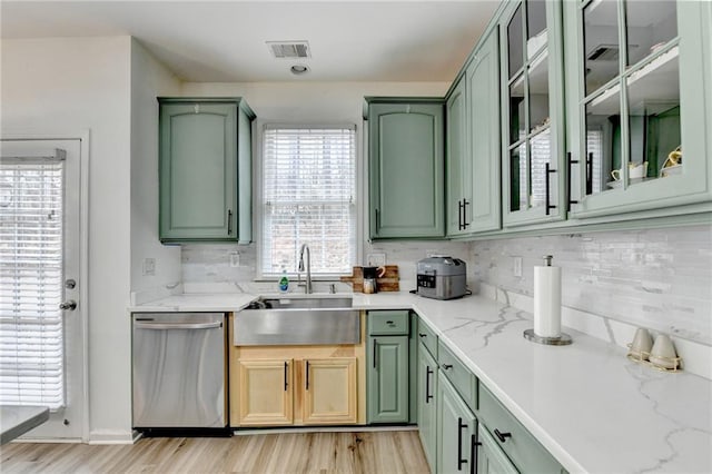 kitchen featuring a sink, green cabinets, decorative backsplash, and stainless steel dishwasher